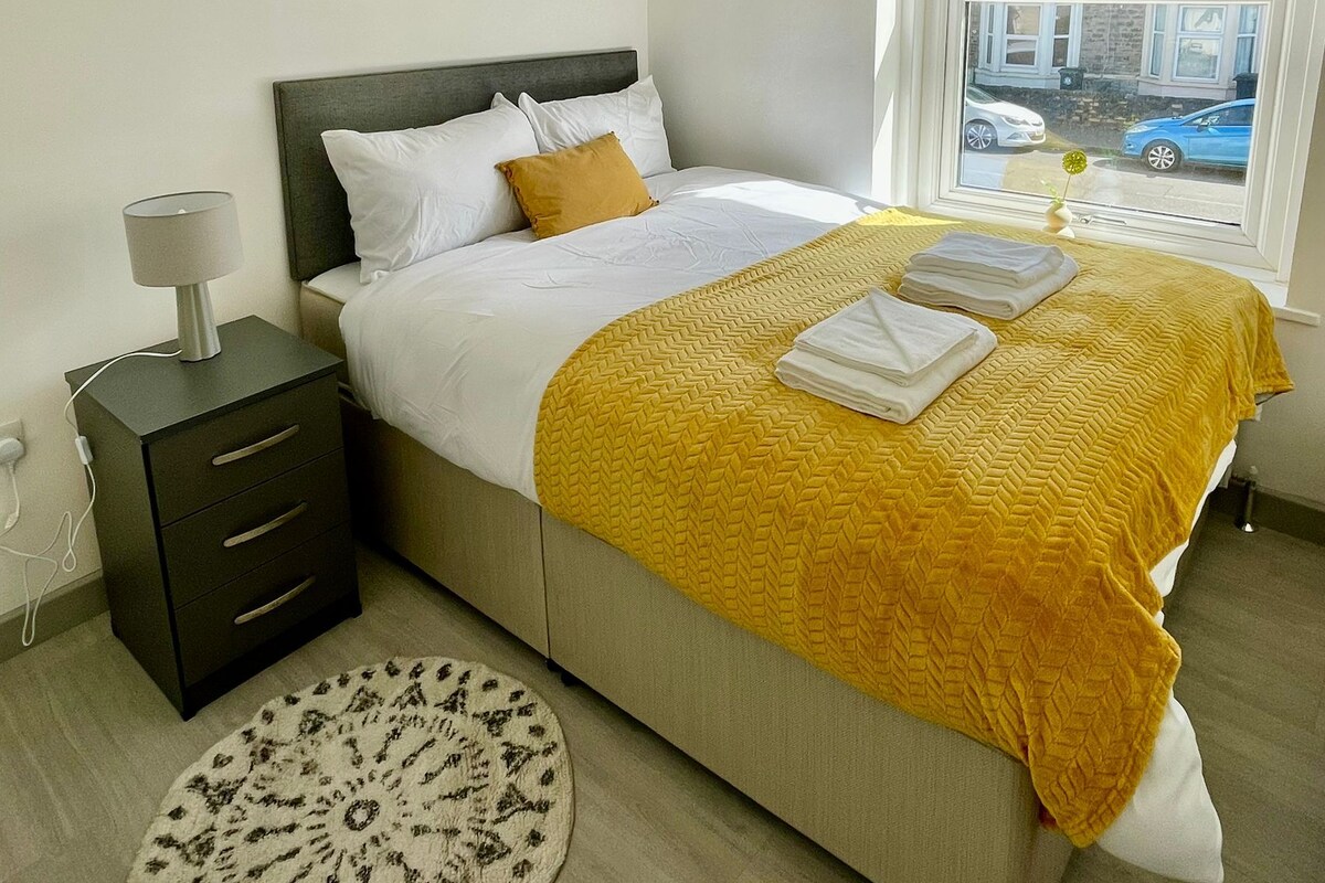 A modern bedroom with a bed, bedside table, lamp, and a round rug.