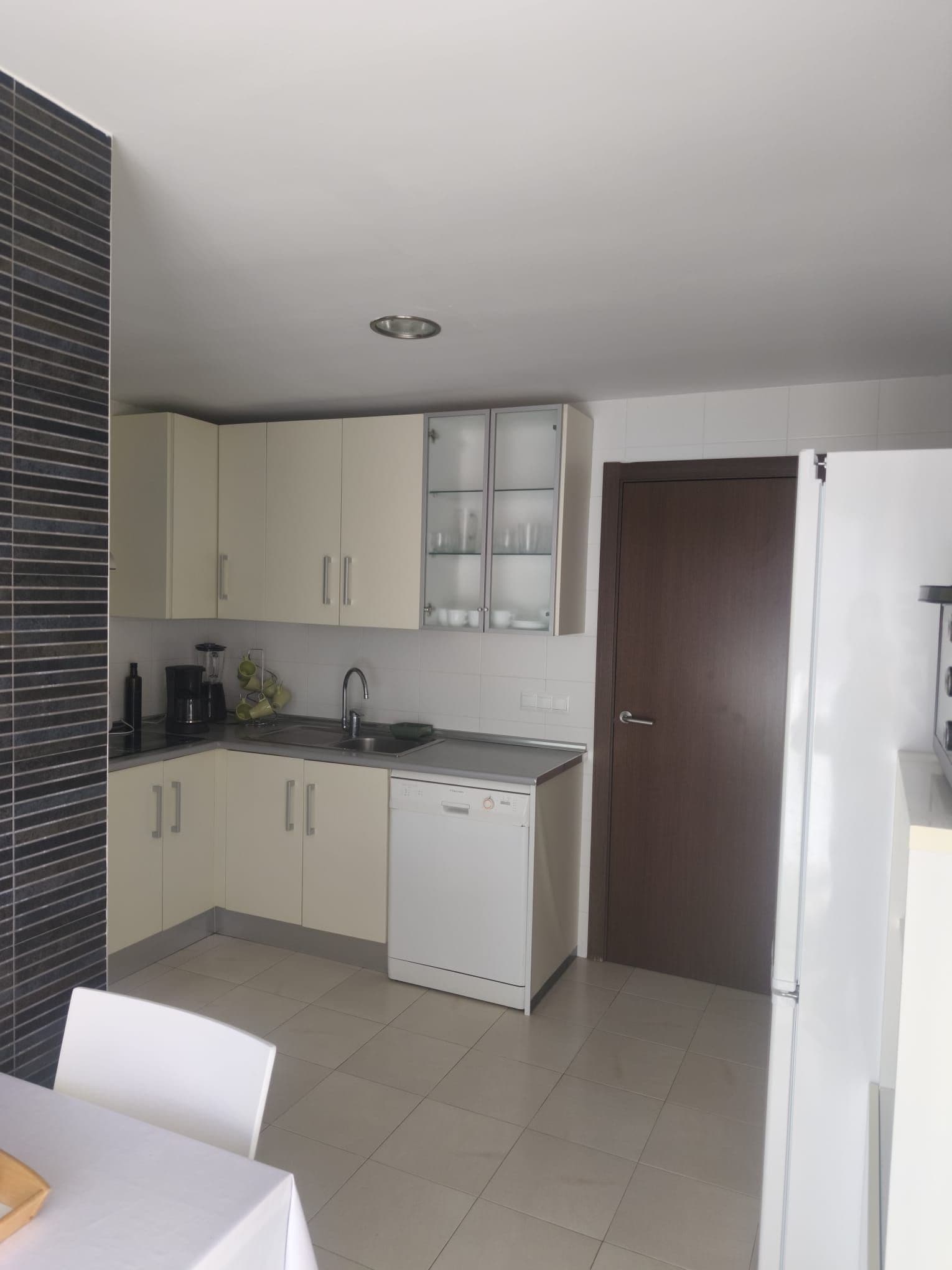 Una cocina moderna con armarios blancos, lavavajillas y pileta.