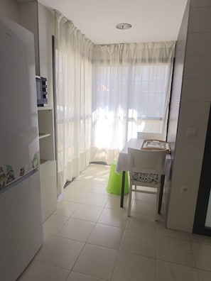 A compact kitchen with a refrigerator, microwave, and a dining area with a table and chairs.