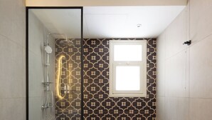 A modern bathroom with a glass shower enclosure, a toilet, and patterned wall tiles. - 88 by spacey (cairo)