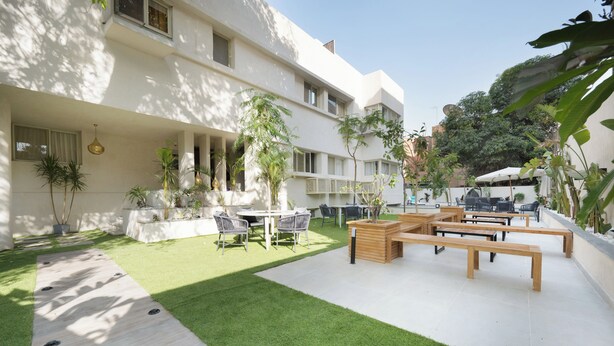 A courtyard with a lawn, outdoor seating, and a building with multiple windows. - 88 by spacey (cairo)