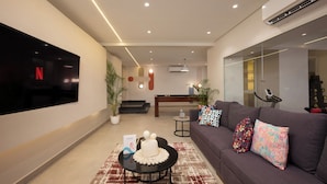 A modern living room with a flat-screen TV, a sofa with patterned cushions, a coffee table with decorative items, and a staircase leading to an upper level. - 88 by spacey (cairo)