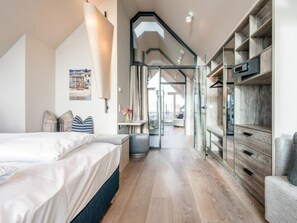 Ein modernes Schlafzimmer mit einem großen Bett, einem Schreibtisch und einem Kleiderschrank.