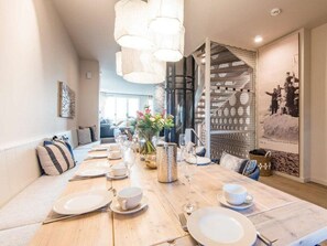Ein Essbereich mit einem Holztisch, gedeckt für eine Mahlzeit, einer dekorativen Vase mit Blumen und einem an der Wand hängenden Bild.