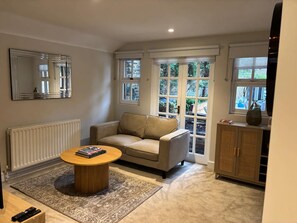 A living room with a sofa, a coffee table, a mirror, and a cabinet. - Elegant St Johns Wood Mews-king Bed Workspace (London)