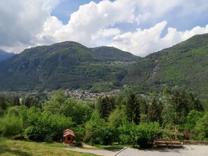 Un paysage rural avec une petite cabane en bois, une végétation luxuriante et un village situé dans la vallée.