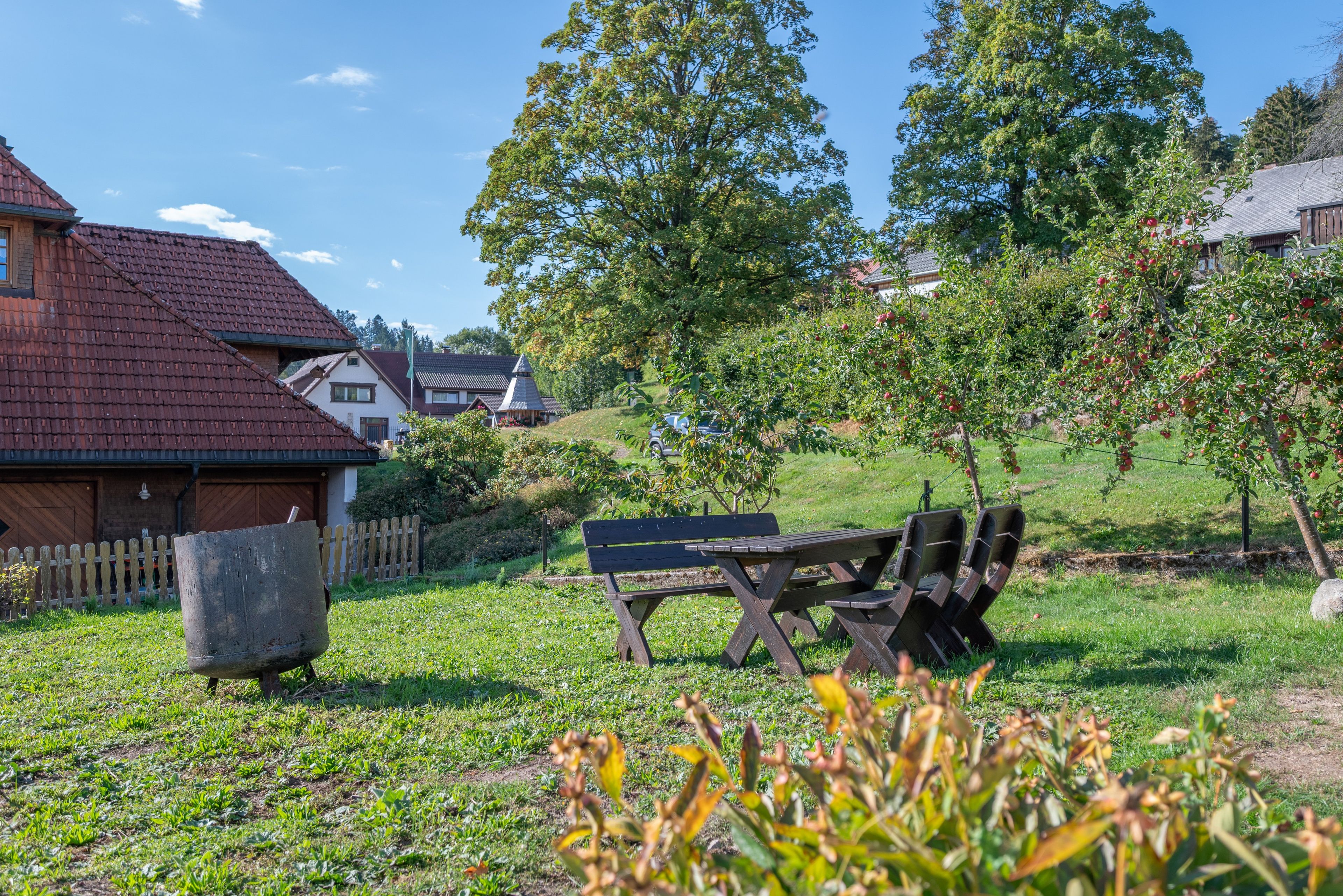 A park with a picnic table and benches, surrounded by trees and a grassy area.