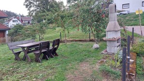 Un espacio al aire libre con mesa de picnic y sillas, rodeado de césped y árboles.