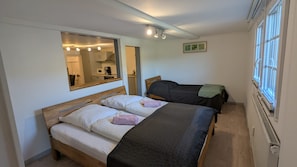 Ein Zimmer mit zwei Betten, einem Spiegel und einem Fenster.