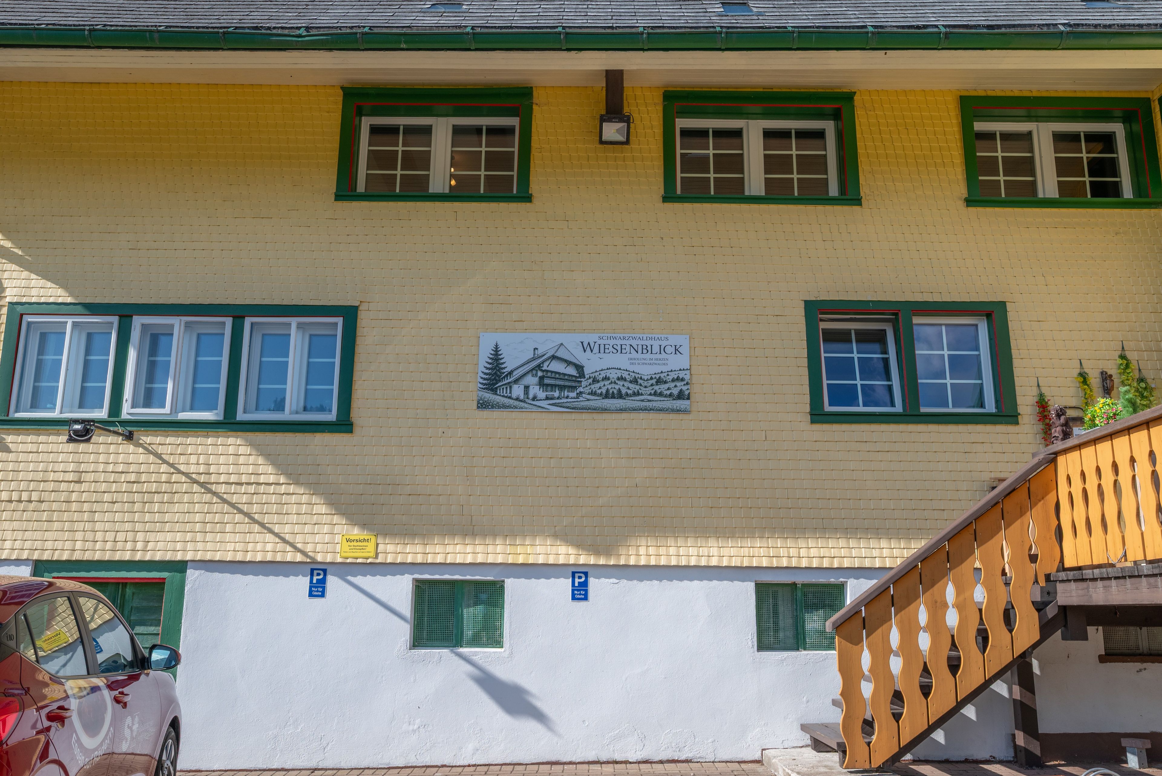 A building with a yellow brick facade, green window frames, and a sign indicating a location named 'Wiesenblick'.