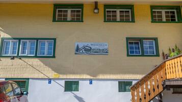 A building with a yellow brick facade, green window frames, and a sign indicating a location named 'Wiesenblick'.