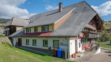 Ein traditionelles Chalet mit steilem Dach, Schornstein und einem Balkon mit Holzwerteln.