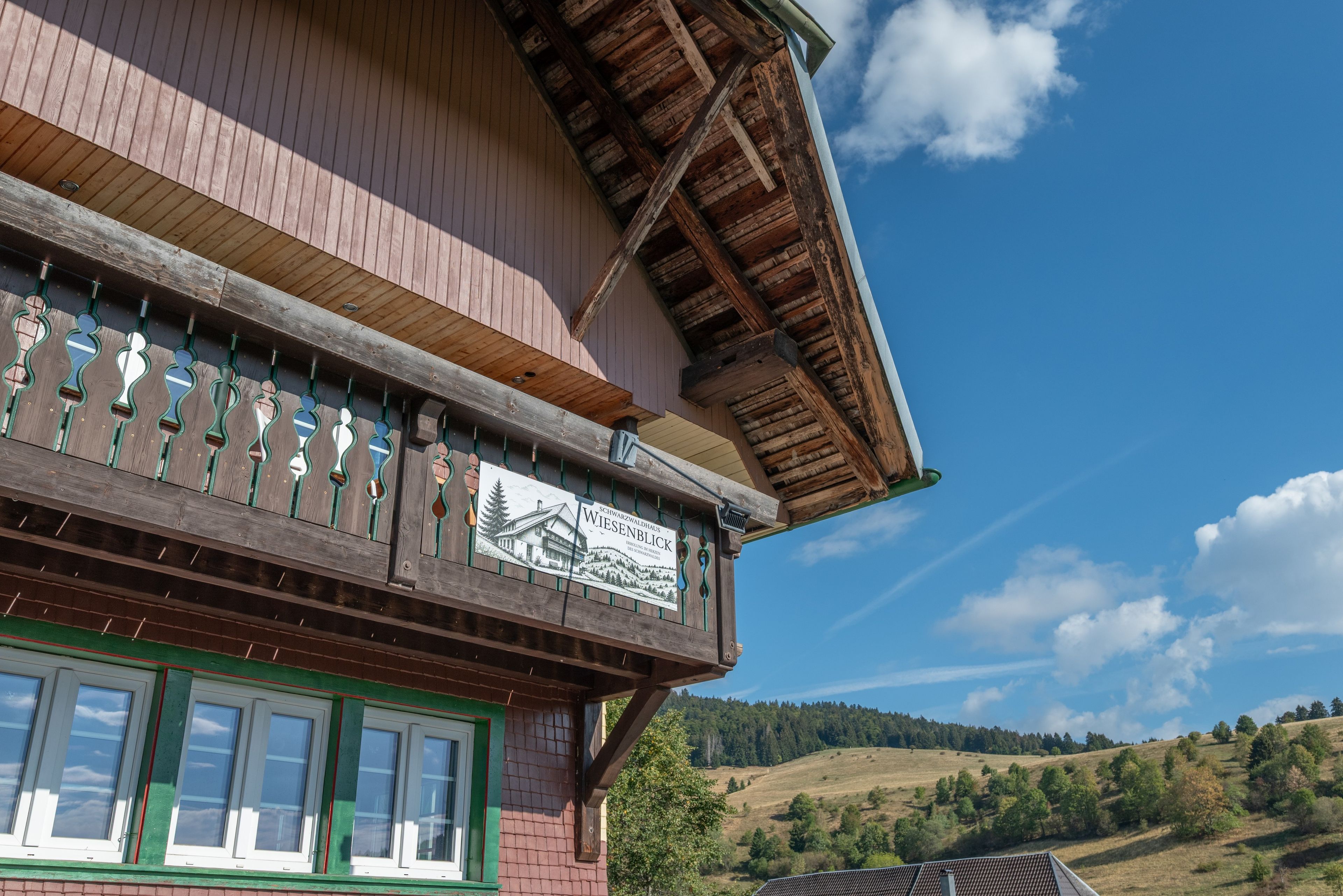 A traditional wooden building with a balcony and a sign indicating it is a guesthouse.