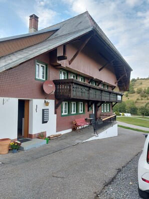 Ein zweigeschossiges Gebäude mit Balkon, Satellitenschüssel und einer kleinen Außen-Sitzgelegenheit.