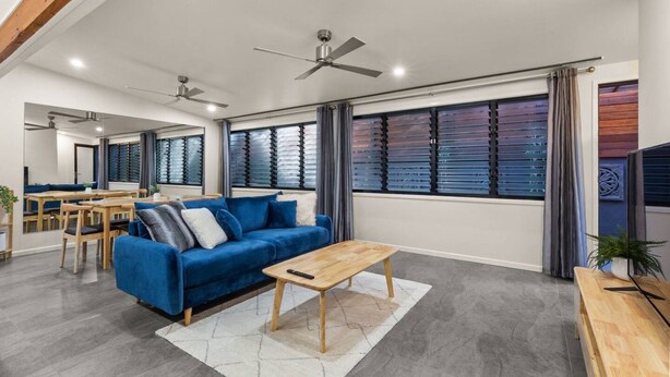A modern living room with a blue sofa, wooden coffee table, and a dining area with a wooden table and chairs. - Private 2BR Villa | Minutes from Brisbane CBD (Spring Hill)