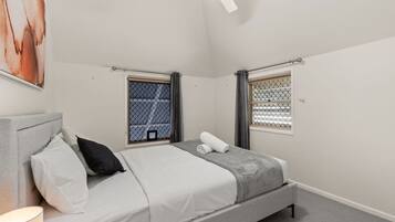 Una camera da letto con un letto, una finestra vista, una ventola a soffitto e un quadro appeso al muro.