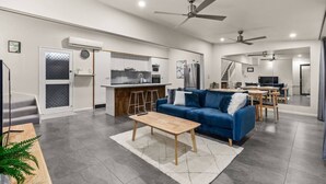 A modern living room with a blue sofa, wooden coffee table, and a kitchen in the background. - Private 2BR Villa | Minutes from Brisbane CBD (Spring Hill)