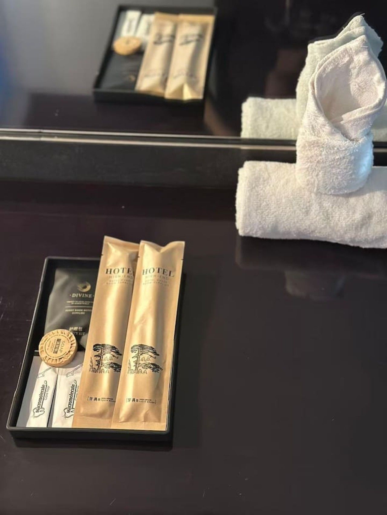 Conjunto de presentes de hotel com produtos de higiene pessoal e uma moeda em uma caixa preta.