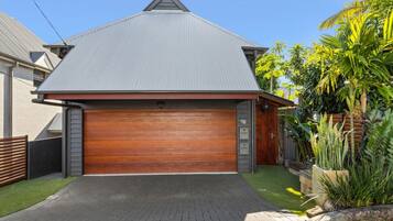 A residential property with a grey roof, a wooden garage door, and a paved driveway.