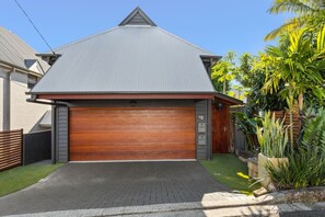 A residential property with a grey roof, a wooden garage door, and a paved driveway. - Spring Hill 1BR Villa | Close to Brisbane CBD (Spring Hill)
