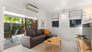 Una sala moderna con un sofá modular, una mesa de centro de madera y un mueble para televisión.