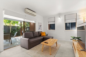 A modern living room with a sectional sofa, a wooden coffee table, and a TV stand. - Spring Hill 1BR Villa | Close to Brisbane CBD (Spring Hill)
