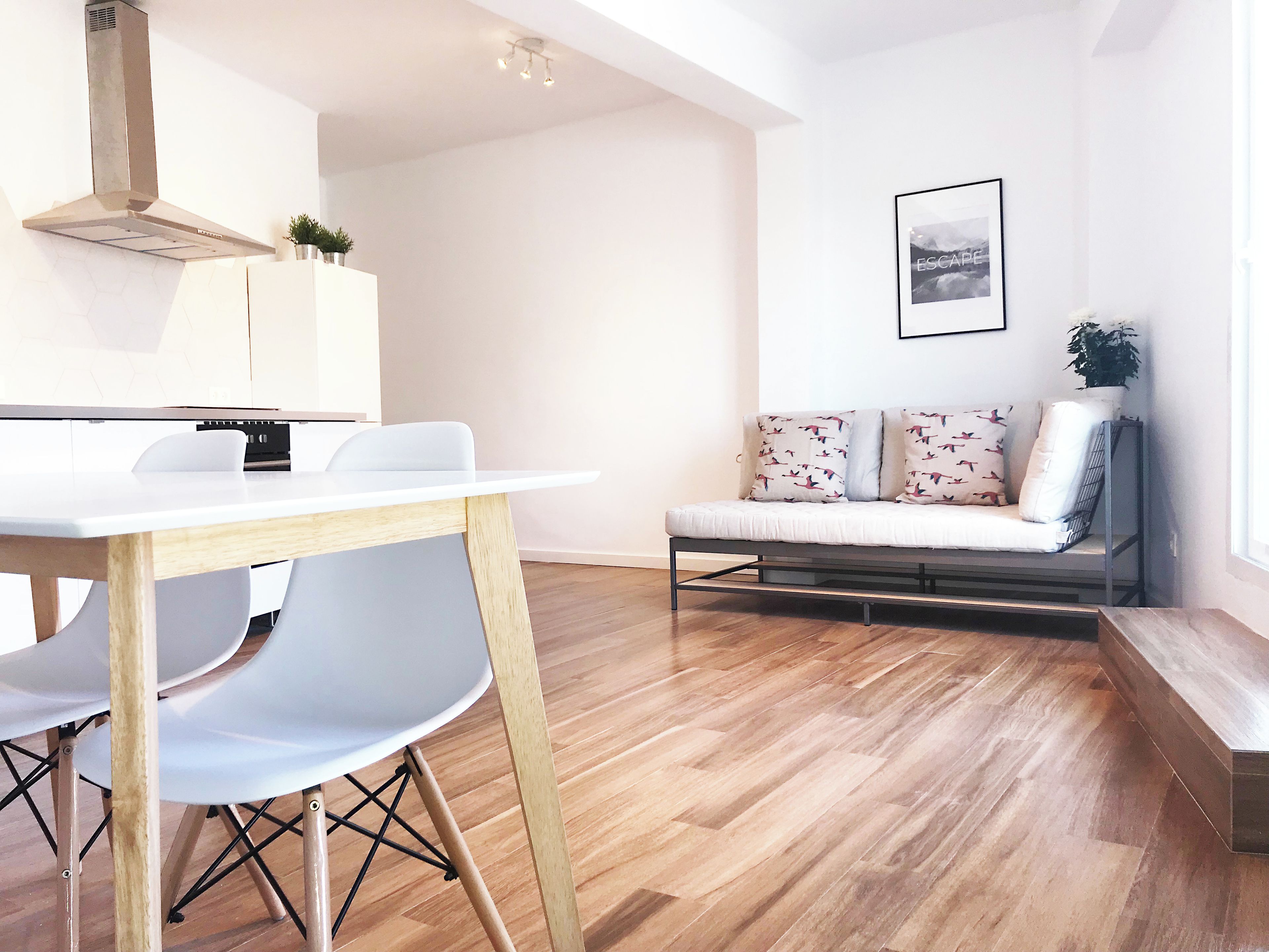 Een moderne keuken met een wit aanrecht, een houten stoel en een eettafel.