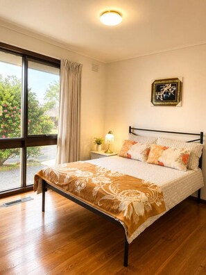 A bedroom with a bed, a nightstand, a lamp, a window with curtains, and a wall-mounted picture. - Cozy 3-Bedroom Home with Parking & Garden (Doncaster)