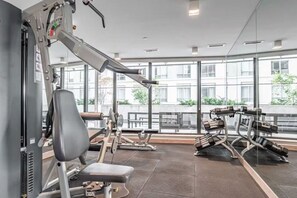 A gym with exercise equipment, large windows, and a view of buildings outside. - *2 Bed Condo* Near UofT/Rogers/Scotia/Hospital/Gym (Toronto)