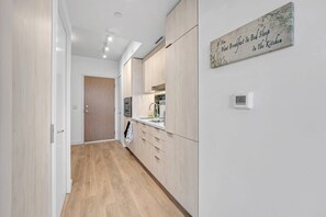A modern kitchen with wooden cabinets, a white countertop, and a wall-mounted clock. - *2 Bed Condo* Near UofT/Rogers/Scotia/Hospital/Gym (Toronto)