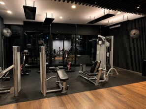 A gym with various exercise machines, a mirror wall, and a wooden floor. - Central Fortitude Valley Stay | 1 Bed, 1 Bath (Fortitude Valley)
