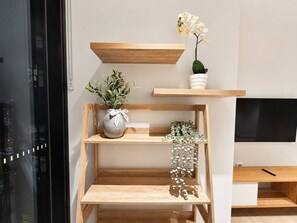 A modern living room with a wooden TV stand, a flat-screen TV, and decorative plants. - Central Fortitude Valley Stay | 1 Bed, 1 Bath (Fortitude Valley)