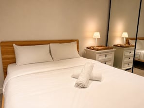 A neatly made bed with white linens and two pillows, a bedside table with a lamp, and a mirror reflecting the room. - Central Fortitude Valley Stay | 1 Bed, 1 Bath (Fortitude Valley)
