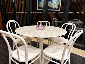 A round table with a marble top surrounded by white chairs. - Central Fortitude Valley Stay | 1 Bed, 1 Bath (Fortitude Valley)
