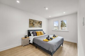 Een moderne slaapkamer met een bed, nachtkastje en een raam.