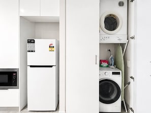 Eine kompakte Küche mit Mikrowelle, Kühlschrank und Waschmaschine.