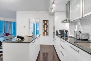 Een moderne keuken met een centraal eiland, witte kastjes en roestvrijstalen apparatuur.