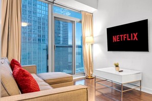 Een moderne woonkamer met een bank, een bijzettafeltje, een lamp en een televisie waarop 'NETFLIX' wordt weergegeven.