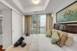 Ein Hotelzimmer mit einem großen Bett, einem Bild an der Wand und Blick aus dem Fenster.