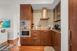 Eine moderne Küche mit Holzausstattung, Edelstahlgeräten und einer gefliesten Spritzschutzwand.