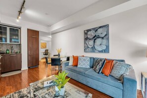 Ein modernes Wohnzimmer mit einem blauen Sofa, einem Couchtisch und einem Essbereich mit Stühlen.
