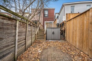 A backyard with a wooden fence, a brick pathway, and a shed. - *Grand House* Sleeps 10 - Vibrant Home next to DT (Toronto)