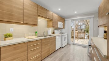 Modern, fully-equipped kitchen with sleek cabinetry and direct access to the back deck.