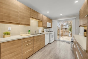 Modern, fully-equipped kitchen with sleek cabinetry and direct access to the back deck.