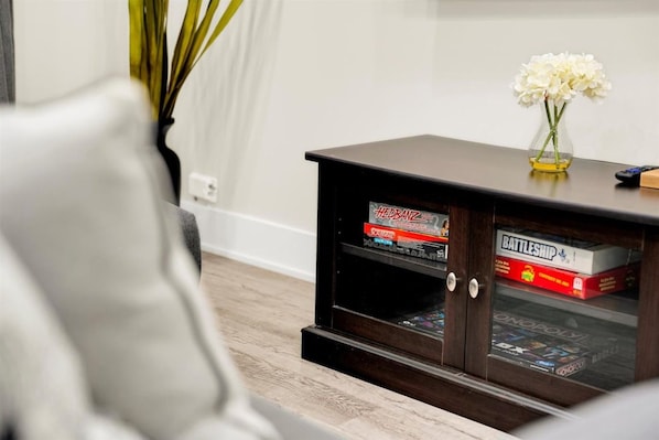 Smart TV and media console stocked with board games—perfect for a cozy movie night or family fun.