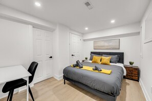 Une chambre moderne avec un lit, une table de chevet et un bureau avec une chaise.