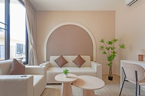 A modern living room with a sofa, two pillows, a small table, a potted plant, and a chair.