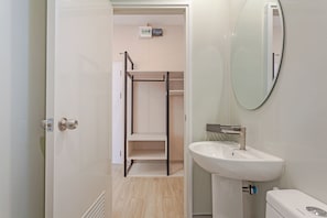 A bathroom with a white sink, a mirror, and a toilet.