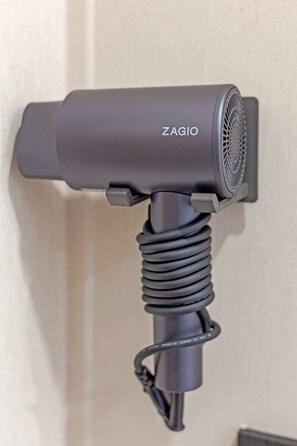 A wall-mounted hair dryer with a coiled cord.
