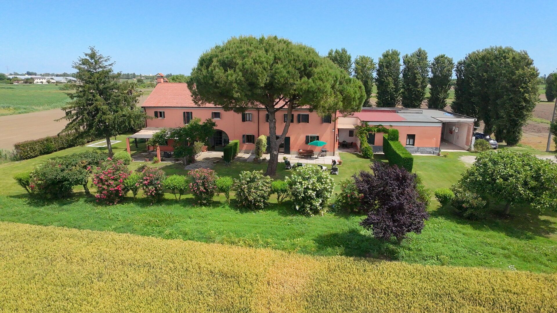 Un edifici gran amb teulada vermella, envoltat de jardins ben cuidats i un camp.